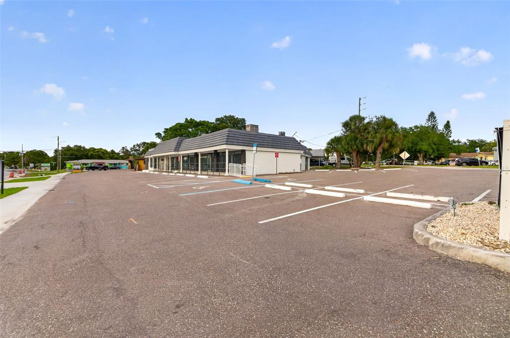 A commercial building with a large asphalt parking lot under a blue sky — 1559 INDIAN ROCKS ROAD S, LARGO, FL