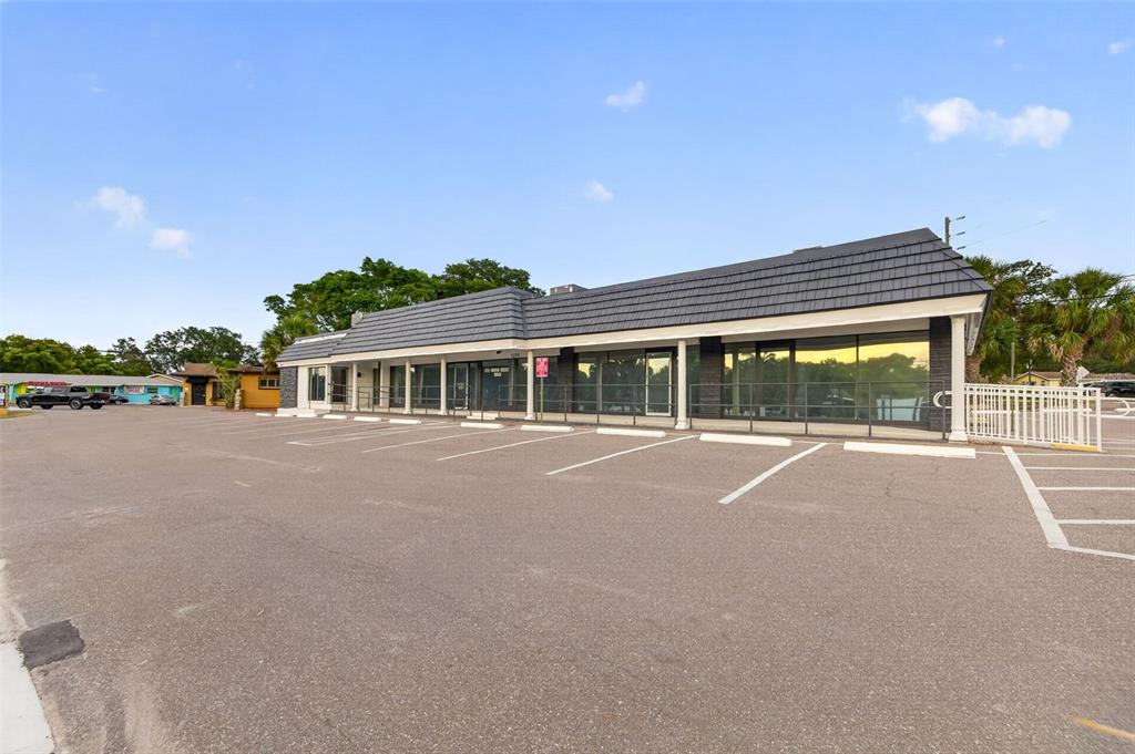 A single-story commercial building with a dark shingled roof and a large paved parking lot — 1559 INDIAN ROCKS ROAD S, LARGO, FL