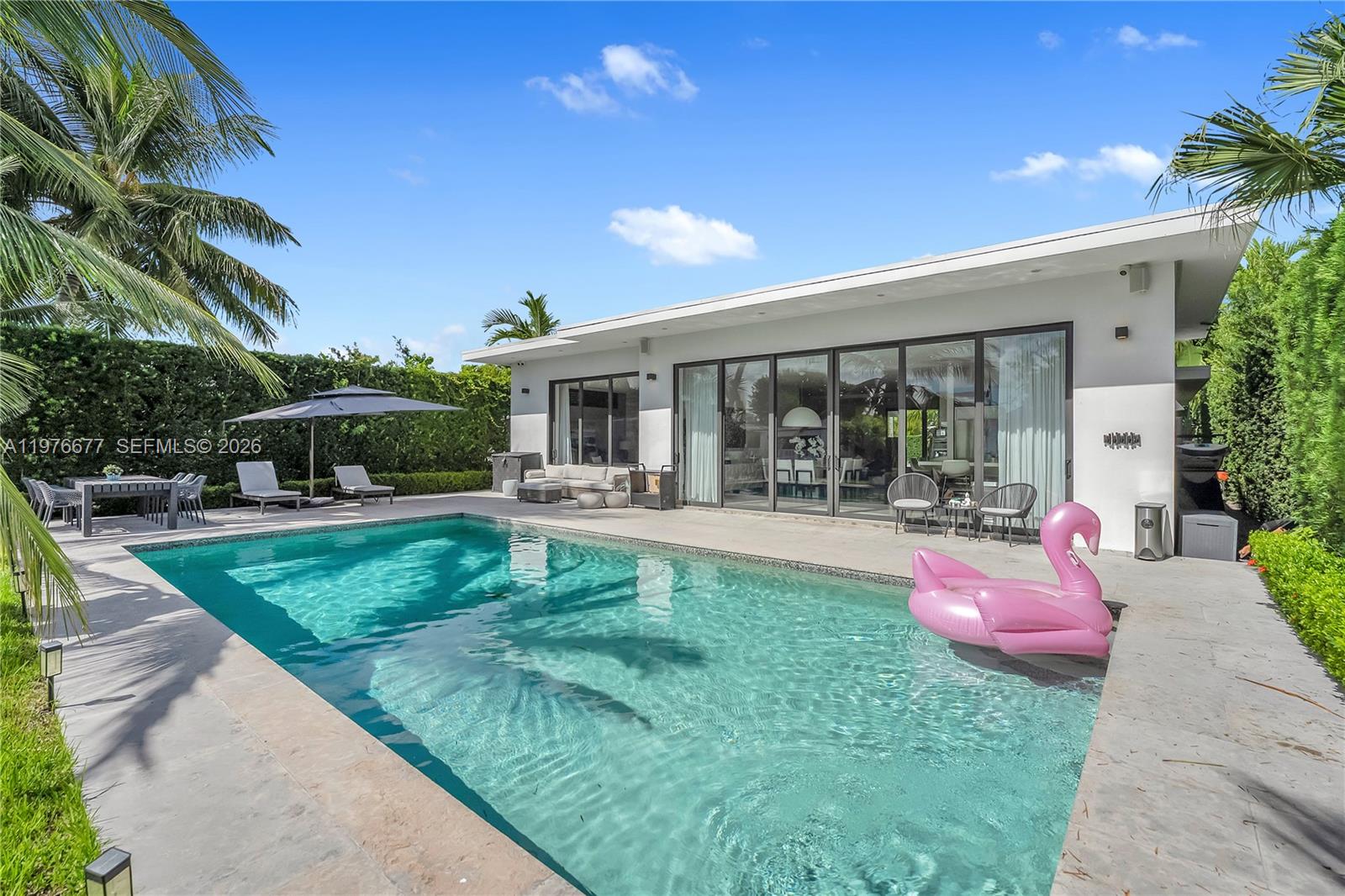 A modern house exterior features a swimming pool with a pink flamingo float — 1540 Cleveland Rd, Miami Beach FL 33141, MIAMI BEACH, FL