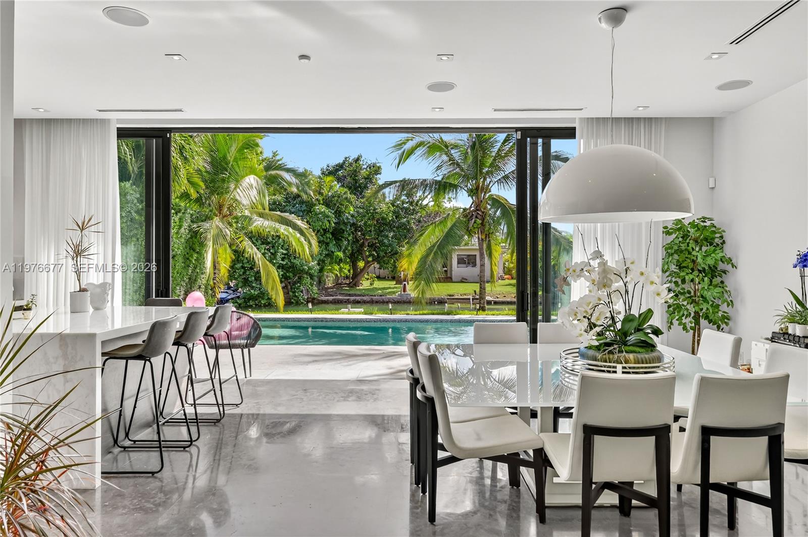 A modern dining and kitchen area opens to a patio with a swimming pool — 1540 Cleveland Rd, Miami Beach FL 33141, MIAMI BEACH, FL