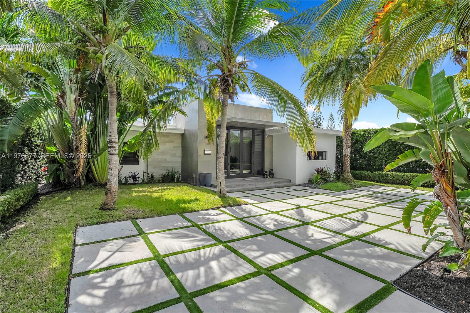 A modern house exterior features a grid-patterned concrete driveway and lush palm trees — 1540 Cleveland Rd, Miami Beach FL 33141, MIAMI BEACH, FL