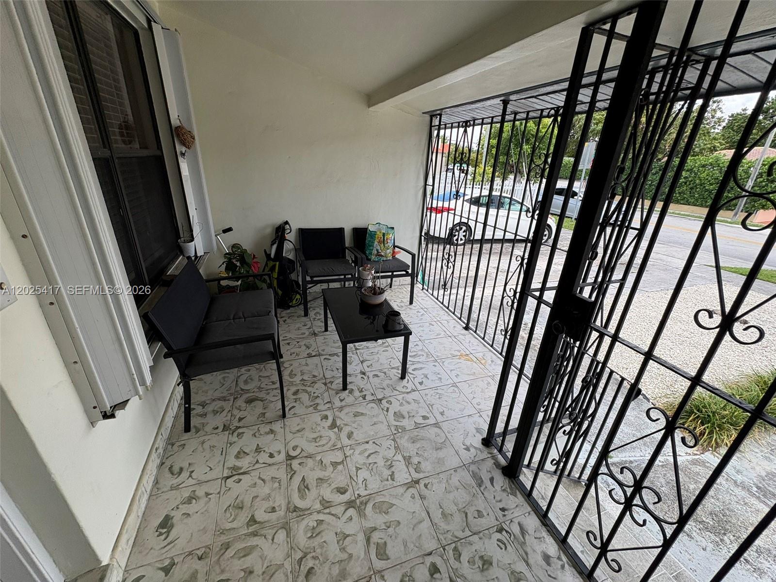 A covered patio features tiled flooring, outdoor seating, and a decorative black metal security gate — 1680 SW 14th Ter, Miami FL 33145, MIAMI, FL