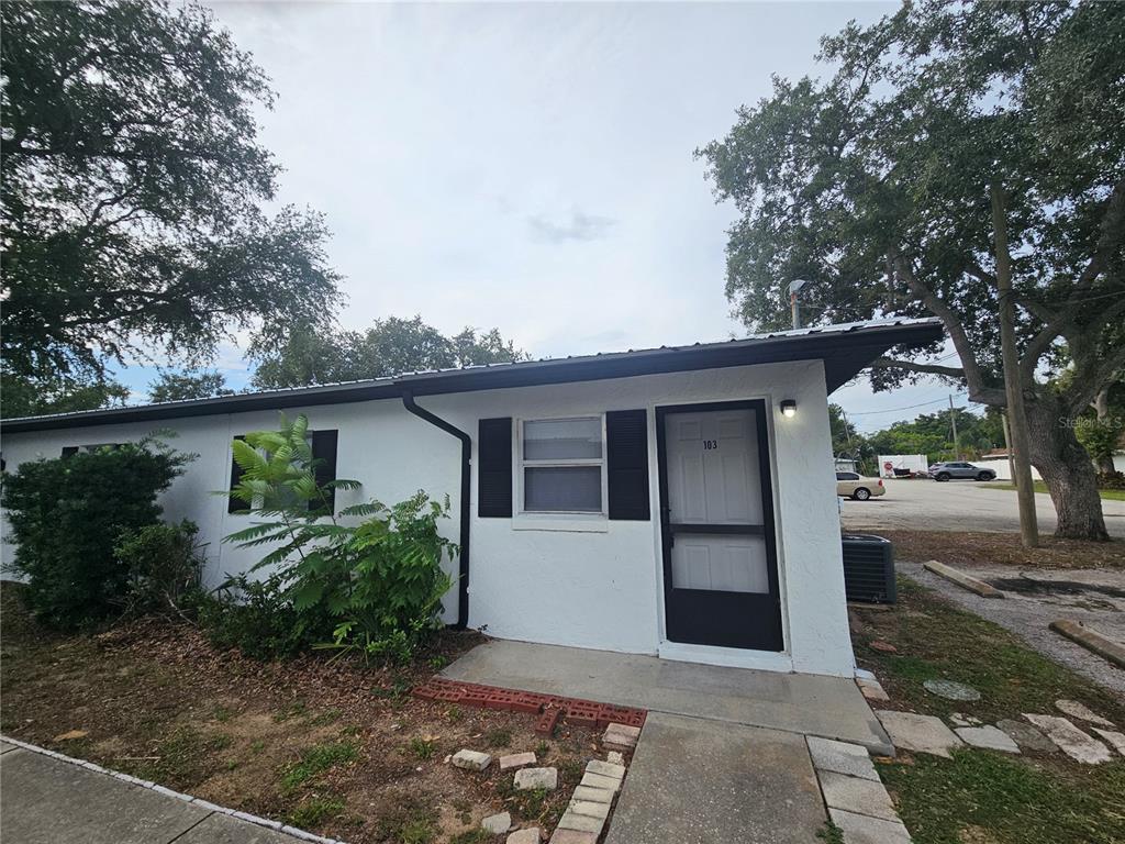 A white, single-story building exterior features a front door labeled 103 and black shutters — 455 S BUCKMOORE ROAD UNIT 103, LAKE WALES, FL
