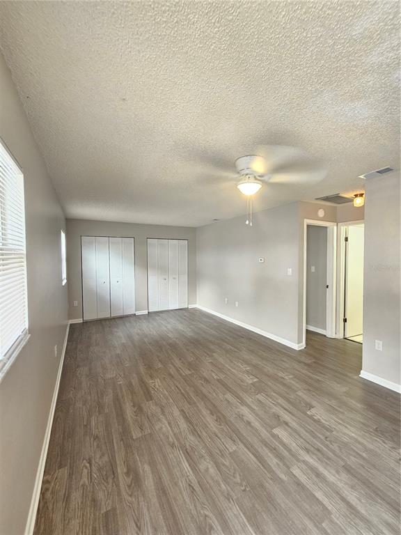 An empty room with light gray walls, wood-look flooring, a ceiling fan, and two closets — 455 S BUCKMOORE ROAD UNIT 103, LAKE WALES, FL