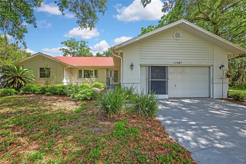 A detached garage with a white door, a side screen door, and a concrete driveway — 11587 W TIMBERLANE DRIVE, HOMOSASSA, FL