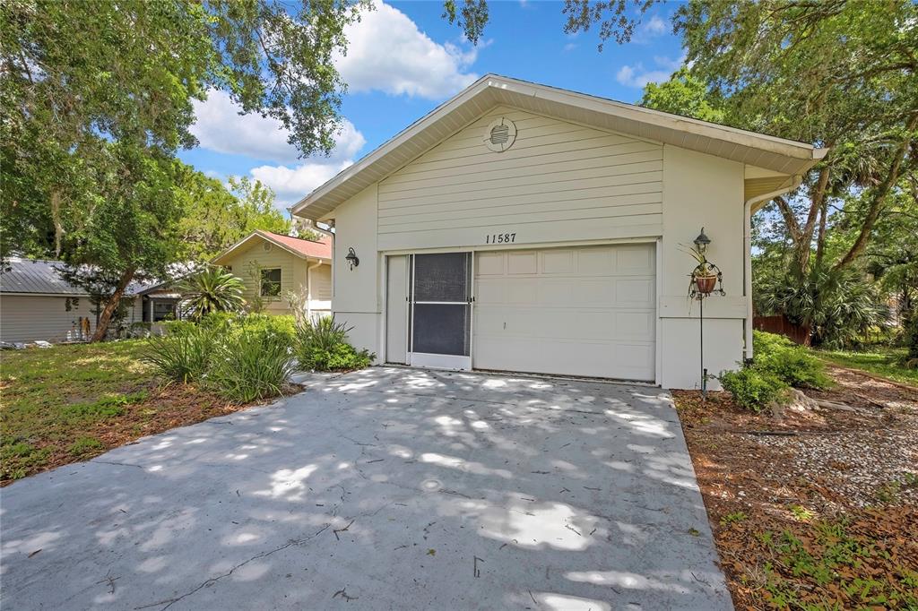 A single-story house with light-colored siding, a red roof, and a large front yard — 11587 W TIMBERLANE DRIVE, HOMOSASSA, FL