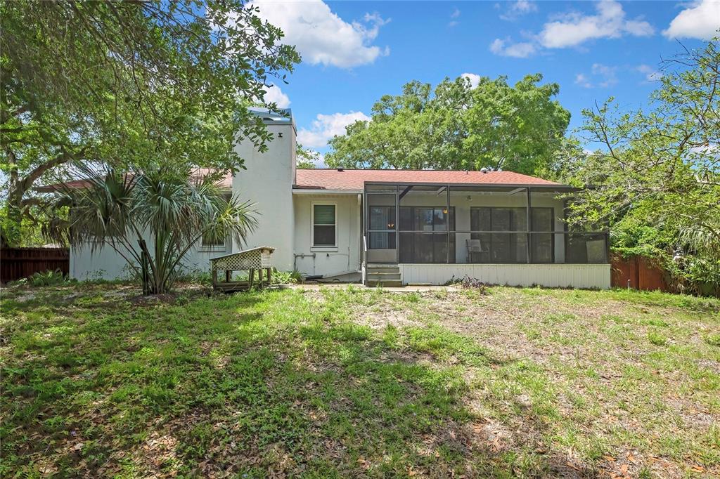 The exterior of a single-story house features a screened-in porch and a large brick chimney — 11587 W TIMBERLANE DRIVE, HOMOSASSA, FL