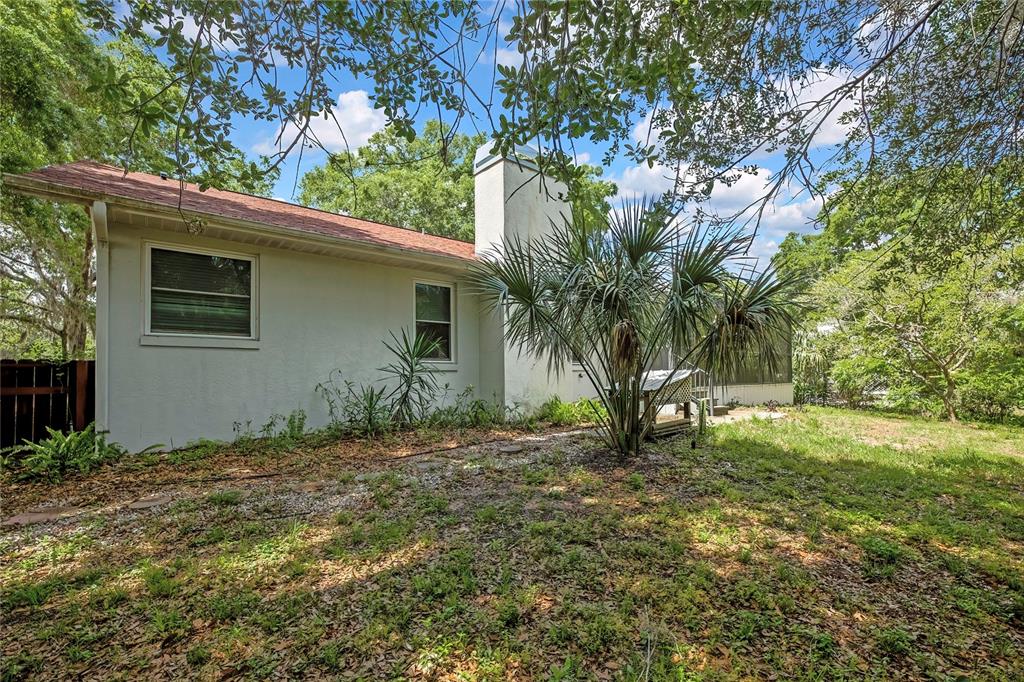 The exterior of a white house features a chimney, a palm tree, and a screened porch — 11587 W TIMBERLANE DRIVE, HOMOSASSA, FL