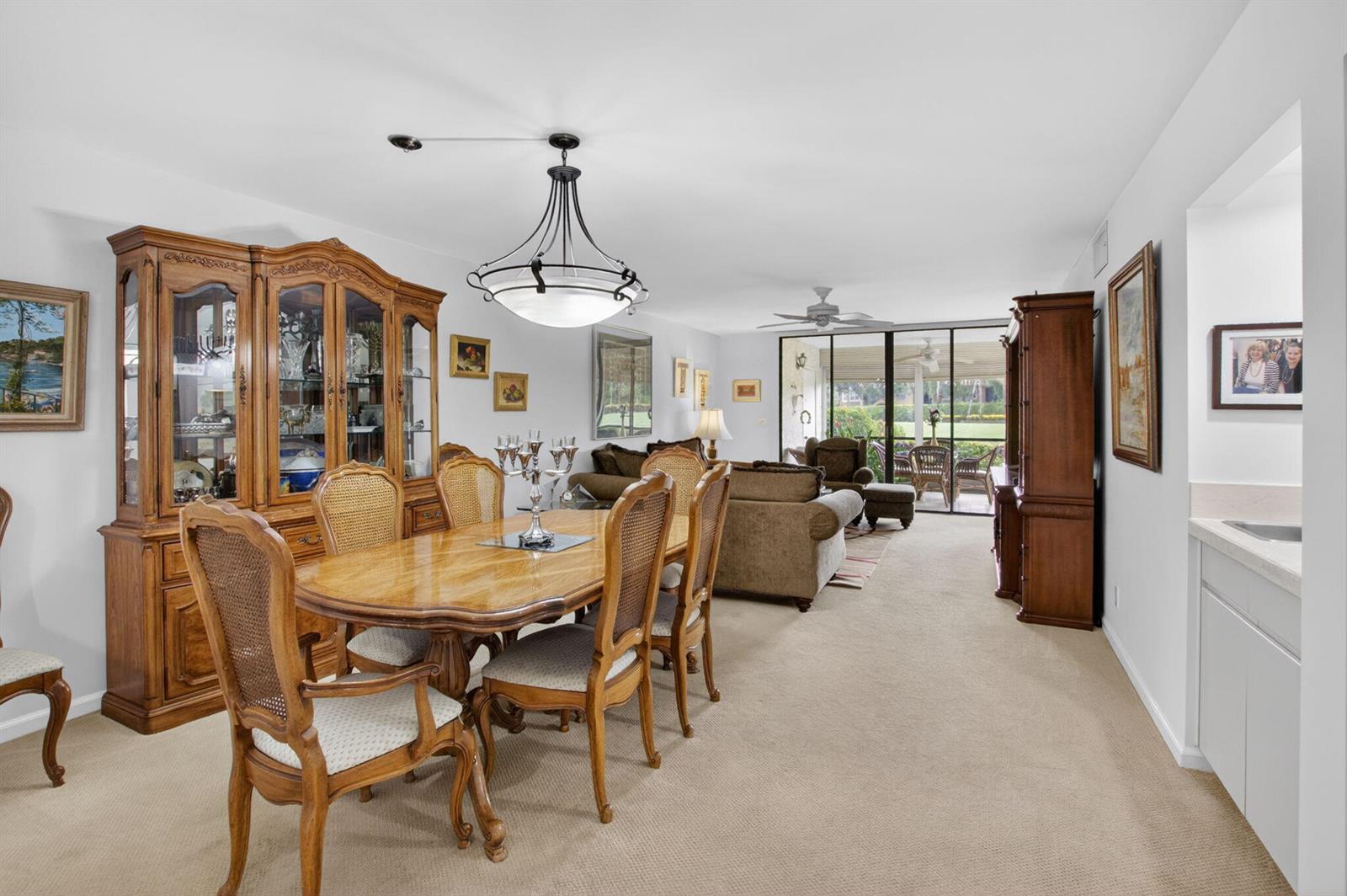 A dining area with a wooden hutch and table leads into a living room with carpet — 15326 Strathearn Drive # 11902, Delray Beach FL 33446, DELRAY BEACH, FL