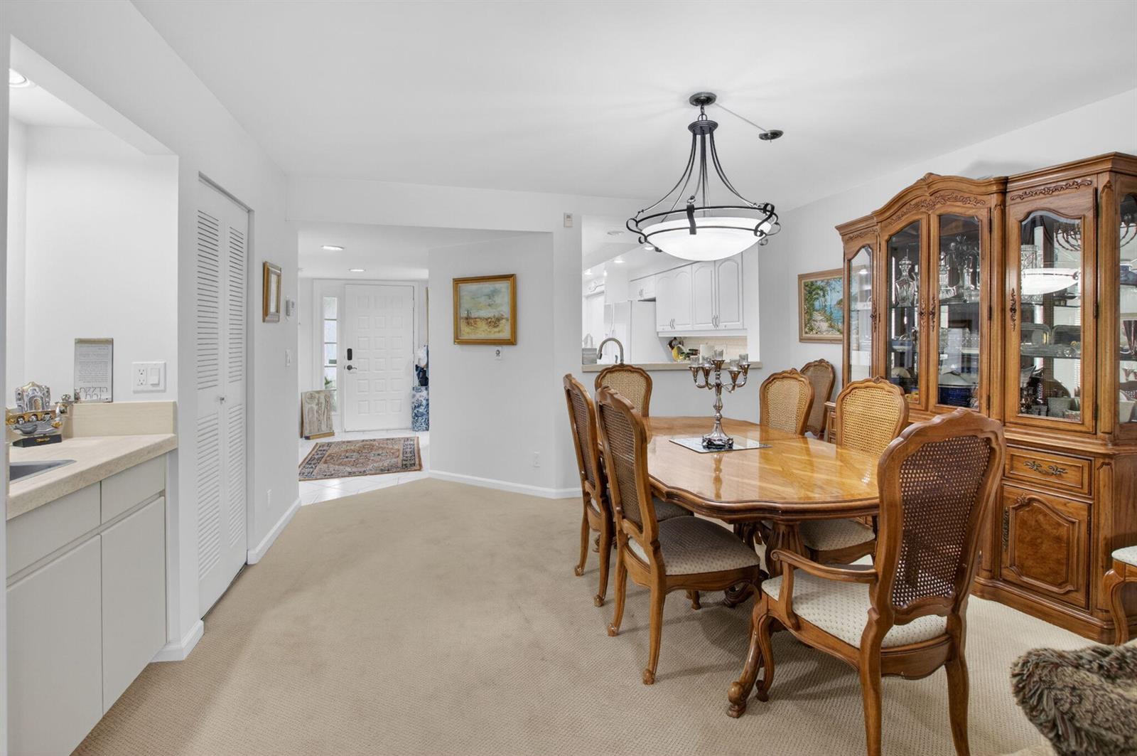 A dining room with a wooden table, chairs, and a large hutch on carpeted flooring — 15326 Strathearn Drive # 11902, Delray Beach FL 33446, DELRAY BEACH, FL