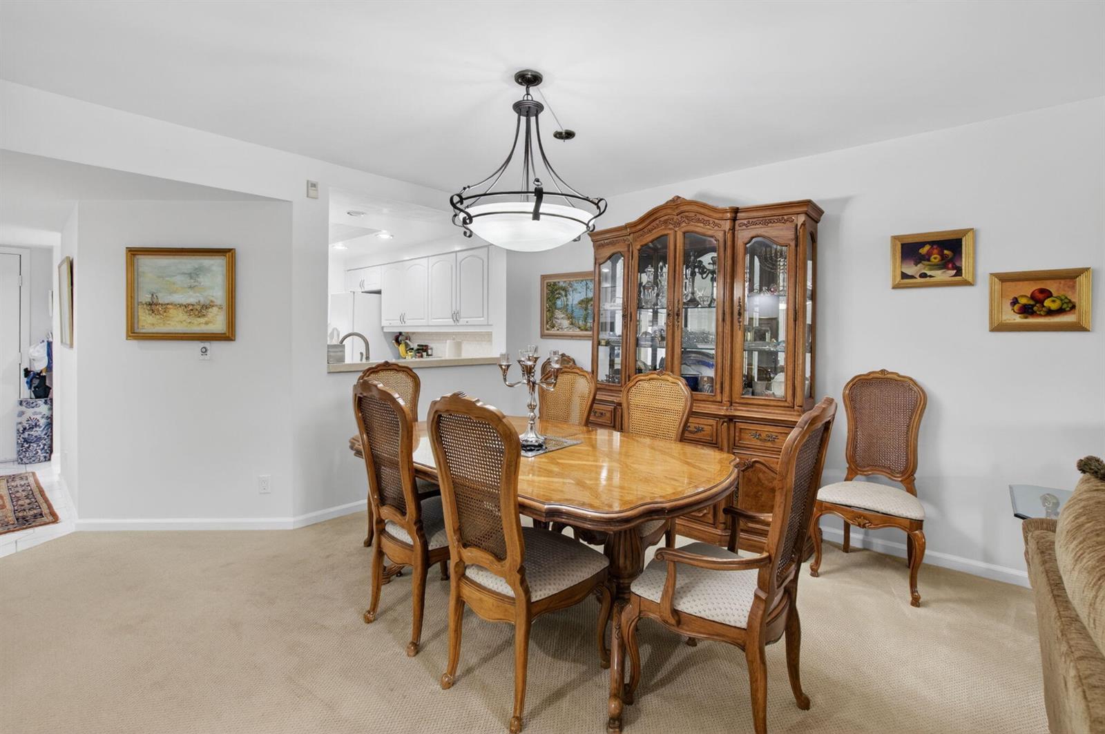 A dining room features a wooden table with cane-back chairs, a large hutch, and chandelier — 15326 Strathearn Drive # 11902, Delray Beach FL 33446, DELRAY BEACH, FL