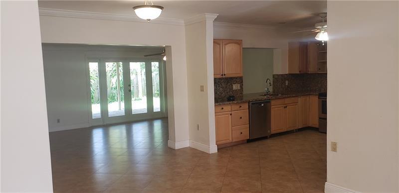 A kitchen with light wood cabinets and granite countertops opens into a bright living area — 98 Seminole Lane, Boca Raton FL 33487, BOCA RATON, FL