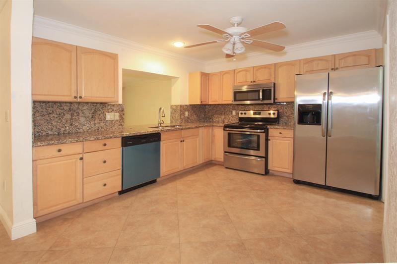 A kitchen with light wood cabinets, granite countertops, stainless steel appliances, and tile flooring — 98 Seminole Lane, Boca Raton FL 33487, BOCA RATON, FL