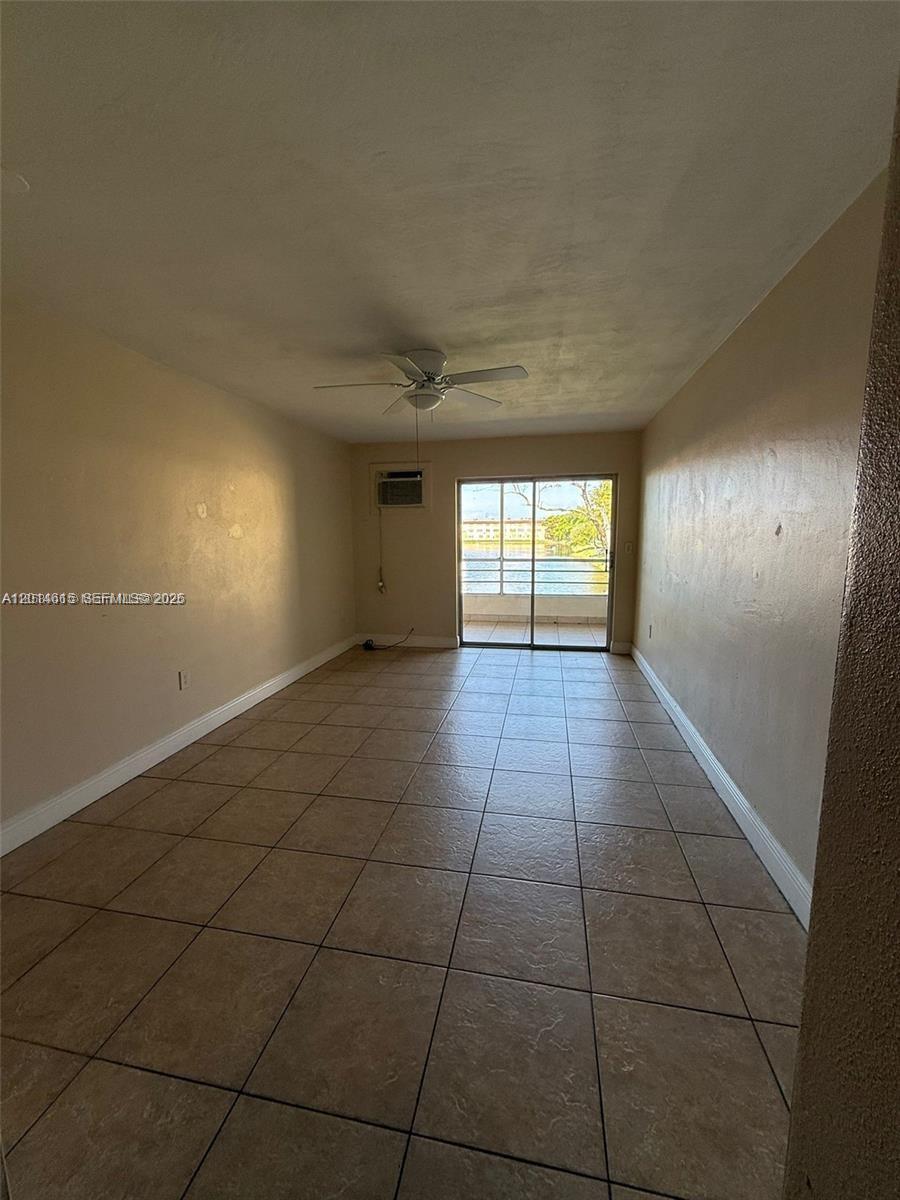 An empty room with tan tile flooring, a ceiling fan, and a sliding glass door — 18707 NE 2nd Ave # 918, Miami FL 33179, MIAMI, FL