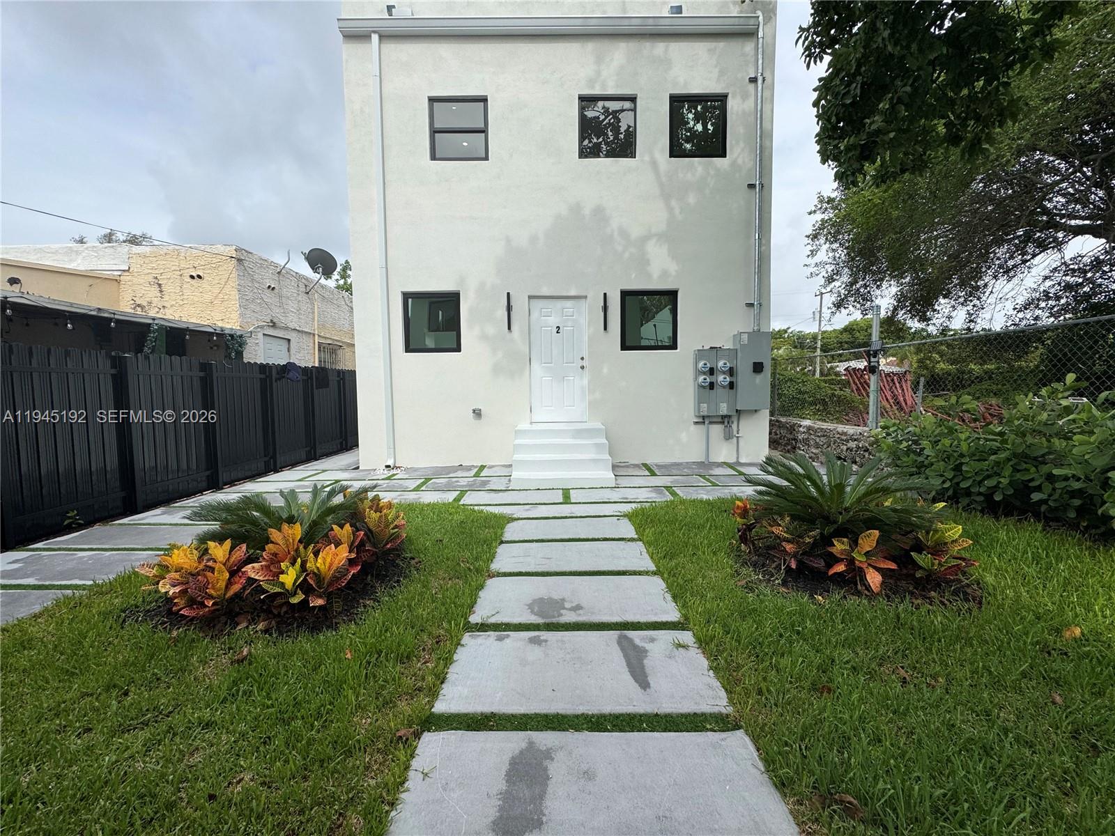 A two-story white building features a central front door, concrete walkway, and landscaped lawn — 905 SW 13th Ct, Miami FL 33135, MIAMI, FL