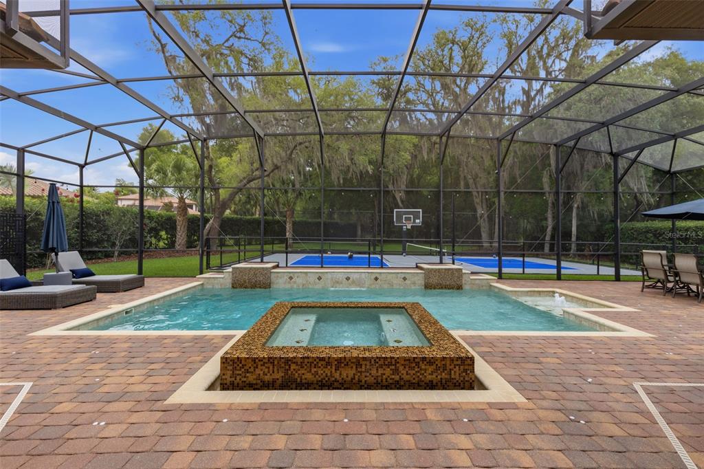 A screened-in patio features a swimming pool, a raised spa, and a backyard sports court — 2218 SOARING EAGLE PLACE, LAKE MARY, FL