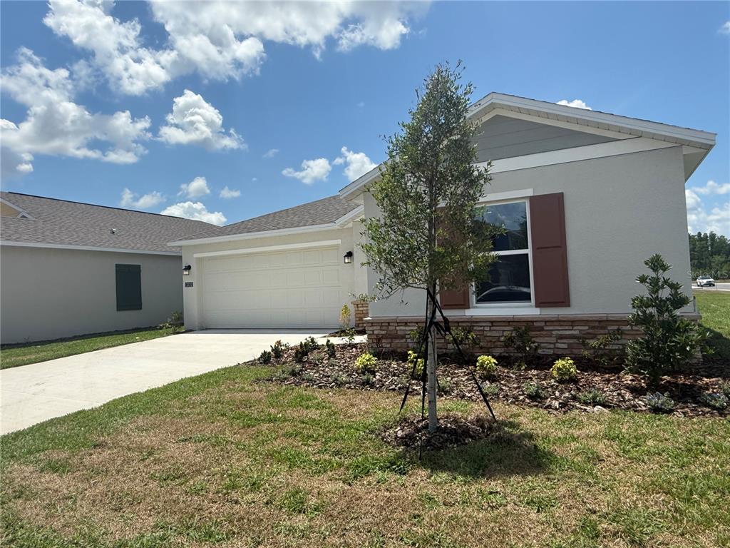 A single-story house with a two-car garage, stone veneer, and brown shutters — 3232 ALPINE WAY, DAVENPORT, FL