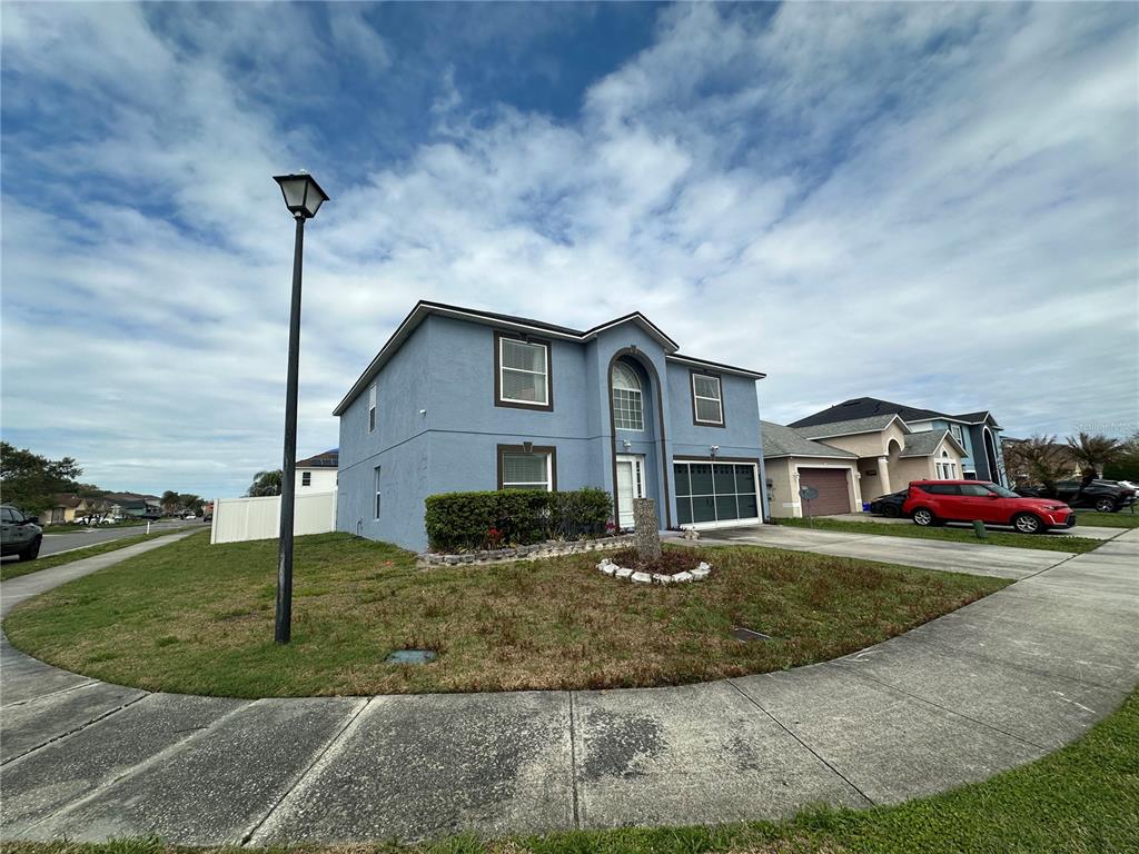 A two-story blue house with a garage and a front yard sits on a corner — 102 WHEATFIELD CIRCLE, SANFORD, FL