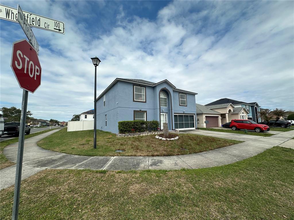 A two-story blue house with a garage sits on a corner lot near a street sign — 102 WHEATFIELD CIRCLE, SANFORD, FL