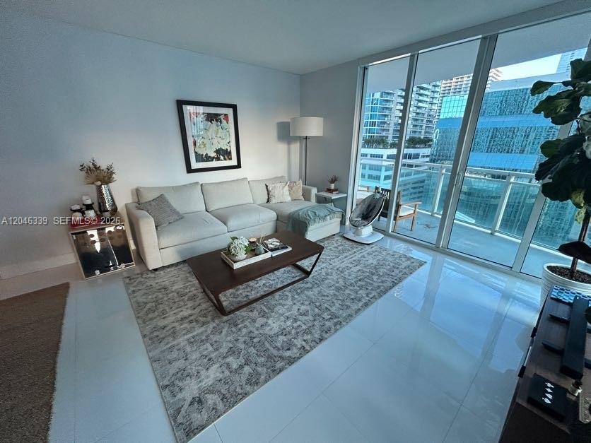 A modern living room features a white sectional sofa, a coffee table, and floor-to-ceiling windows — 951 Brickell Ave # 2011, Miami FL 33131, MIAMI, FL