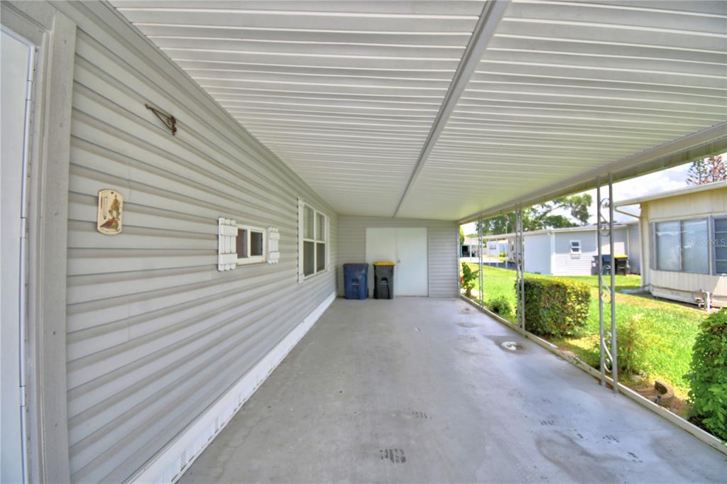 A covered concrete carport area attached to the side of a light gray mobile home — 118 PARADISE LANE, AUBURNDALE, FL