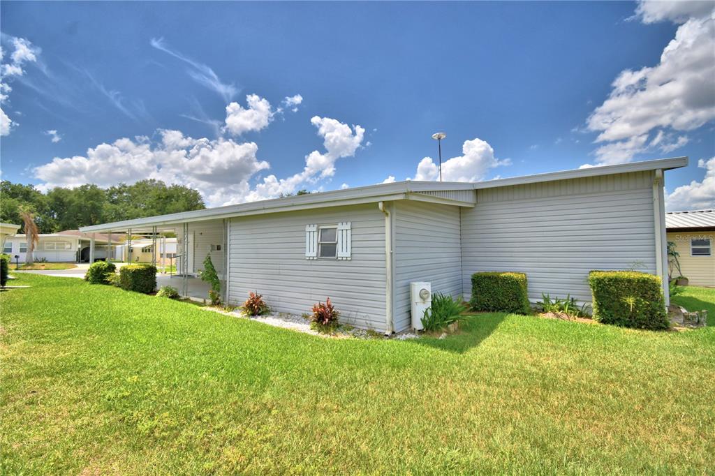 A side view of a single-story home with light gray siding and a covered carport — 118 PARADISE LANE, AUBURNDALE, FL