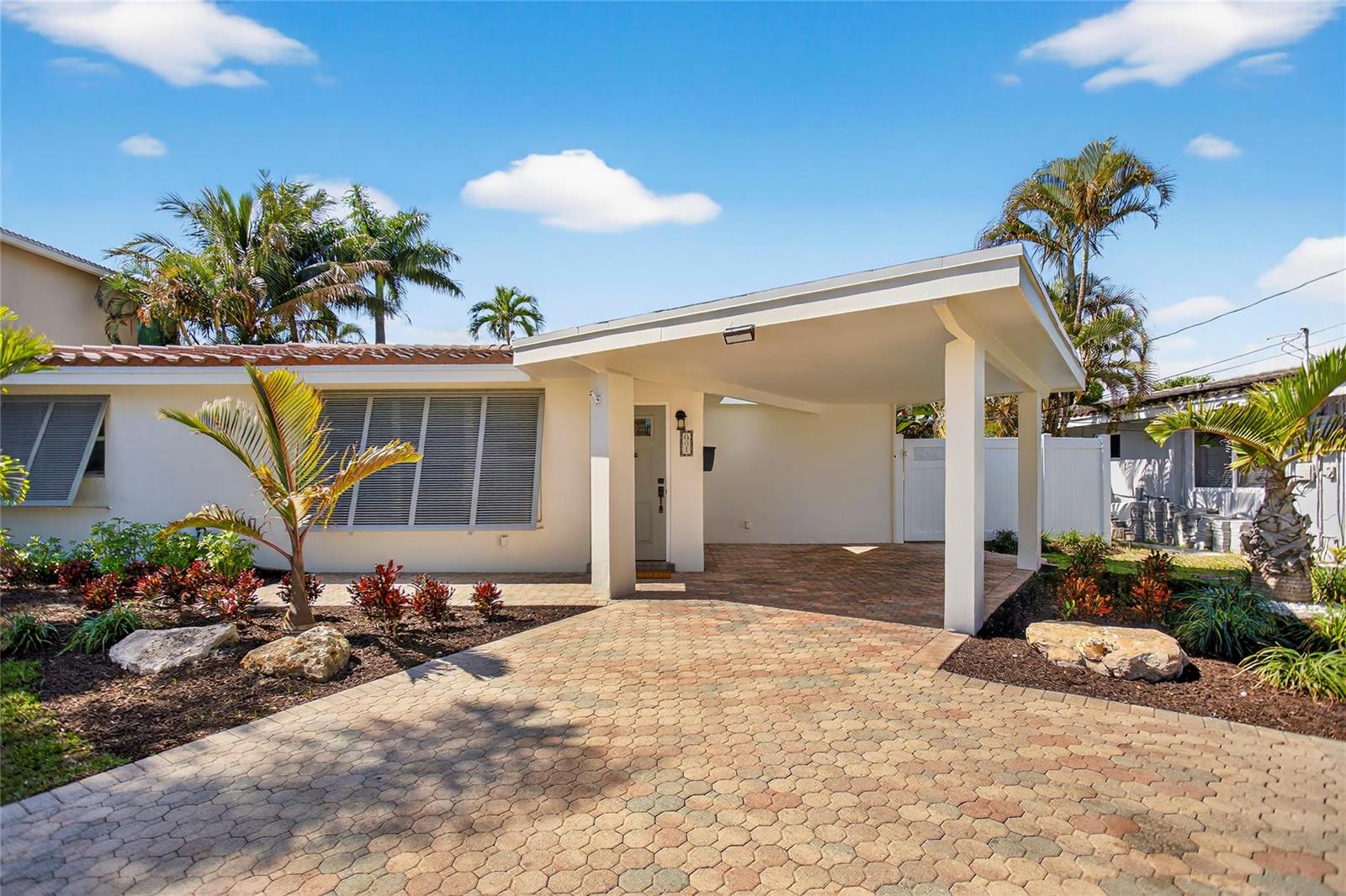 A single-story house with a paved driveway, a carport, and tropical landscaping under a blue sky — 601 SE 5th Terrace, Pompano Beach FL 33060, POMPANO BEACH, FL