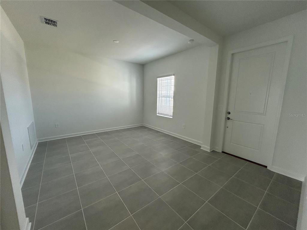 An empty room features gray tile flooring, white walls, a single window, and a white door — 3008 ELLA WAY, ST CLOUD, FL
