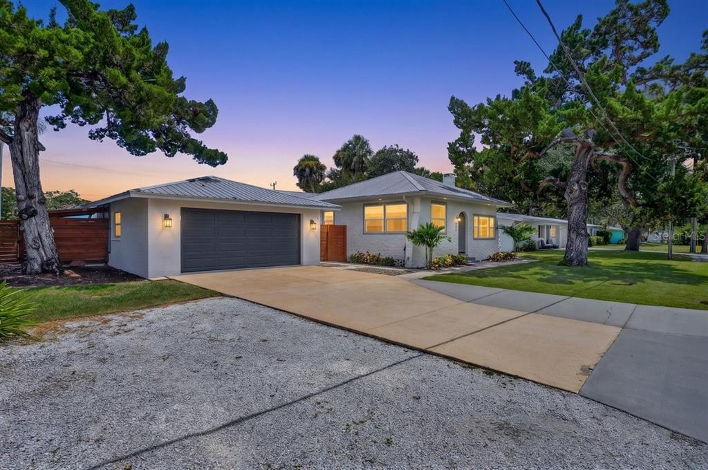 A single-story house with a metal roof, attached garage, and a gravel and concrete driveway — 507 GOODWIN AVENUE, NEW SMYRNA BEACH, FL