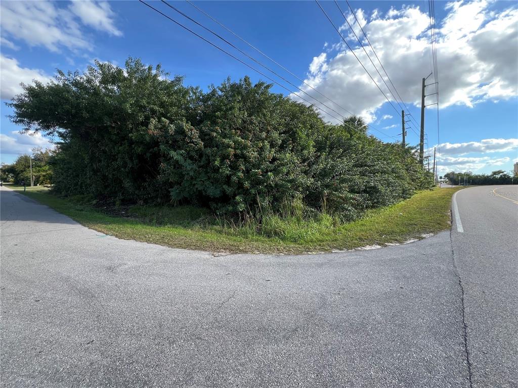 A corner lot with dense green vegetation sits at the intersection of two paved roads — 2620 COOPER STREET, PUNTA GORDA, FL