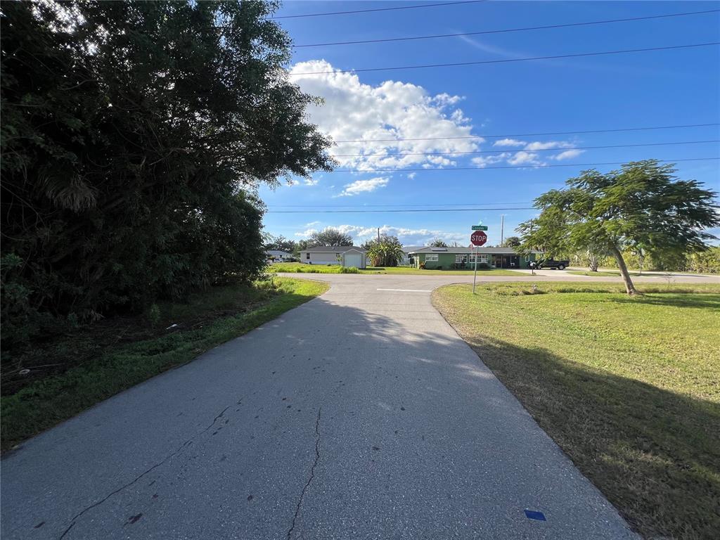 A paved road leads to a T-intersection with a stop sign and a green house — 2620 COOPER STREET, PUNTA GORDA, FL