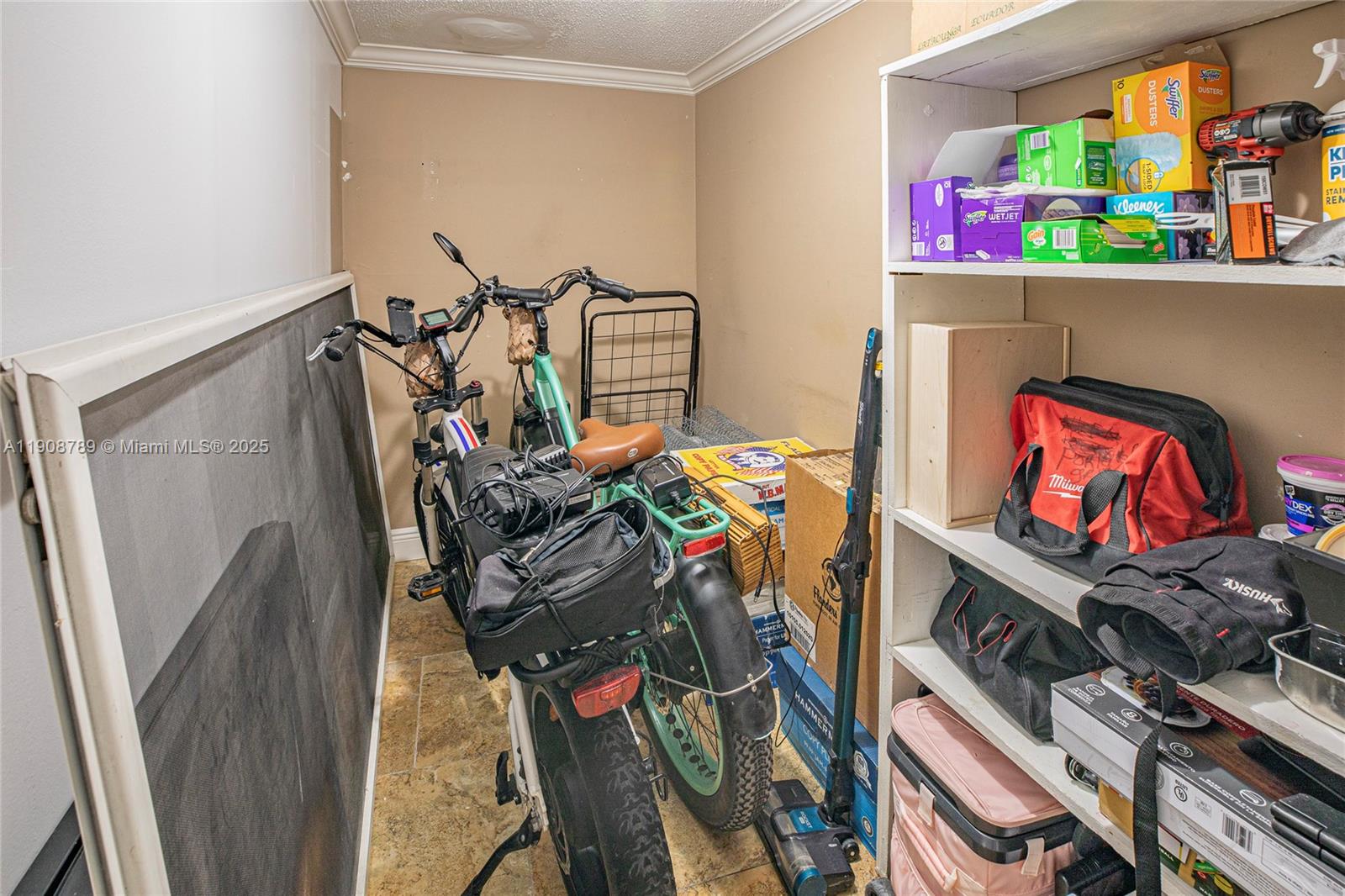 A storage room contains two bicycles, a shelving unit with various items, and miscellaneous boxes — 437 Golden Isles Dr # C, Hallandale Beach FL 33009, HALLANDALE BEACH, FL