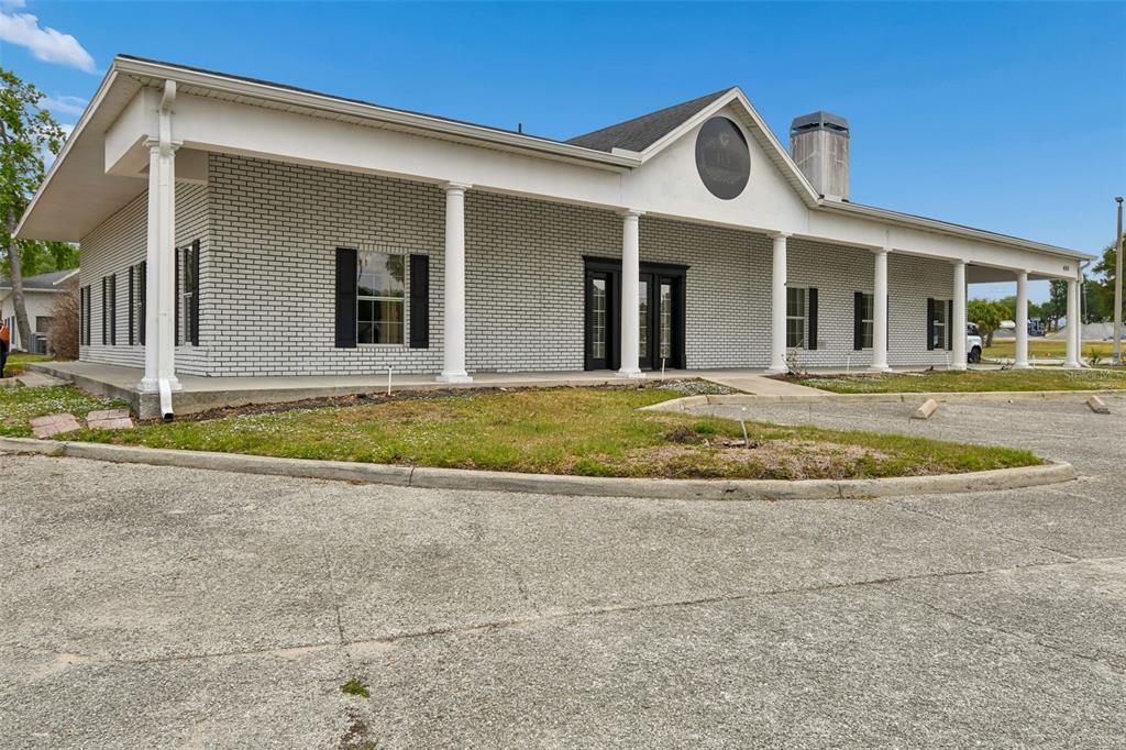 A single-story white brick building with a covered porch and columns under a blue sky — 450 E HIGHWAY 50, CLERMONT, FL