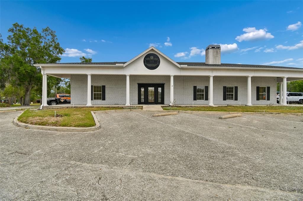 A single-story commercial building with a white brick facade, columns, and a front parking lot — 450 E HIGHWAY 50, CLERMONT, FL