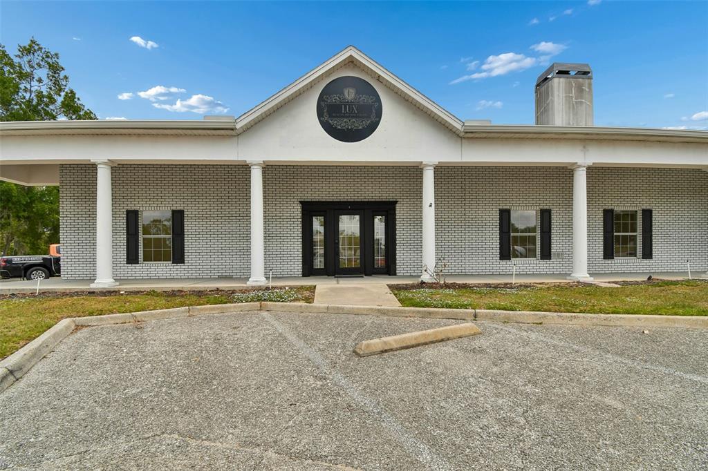 A single-story commercial building with a white brick facade, black shutters, and a covered porch — 450 E HIGHWAY 50, CLERMONT, FL
