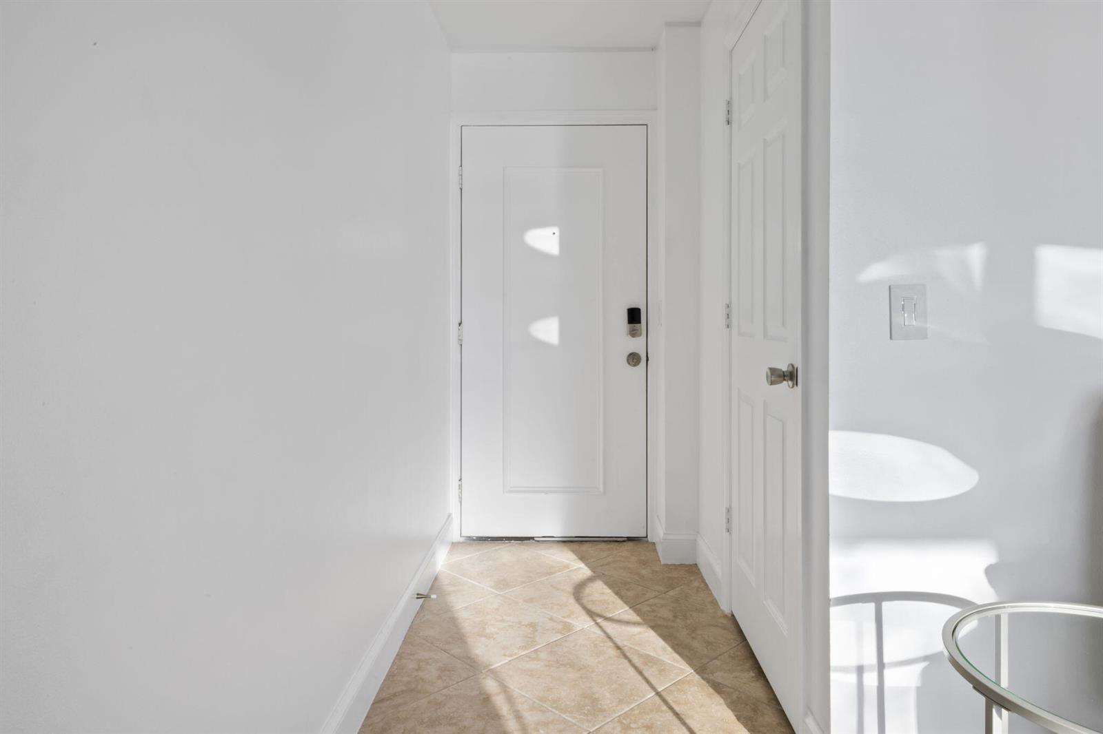 A white front door stands at the end of a tiled entryway with a closet — 1907 Aynsley Way # 321, Vero Beach FL 32966, VERO BEACH, FL
