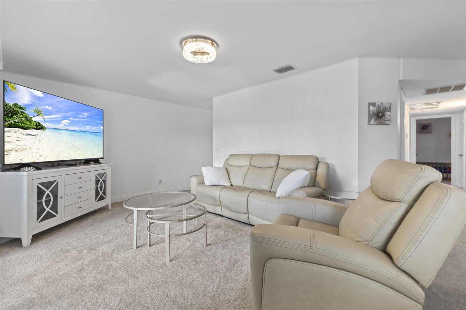 A living room features a white media console, a beige leather sofa, and a matching recliner — 1907 Aynsley Way # 321, Vero Beach FL 32966, VERO BEACH, FL