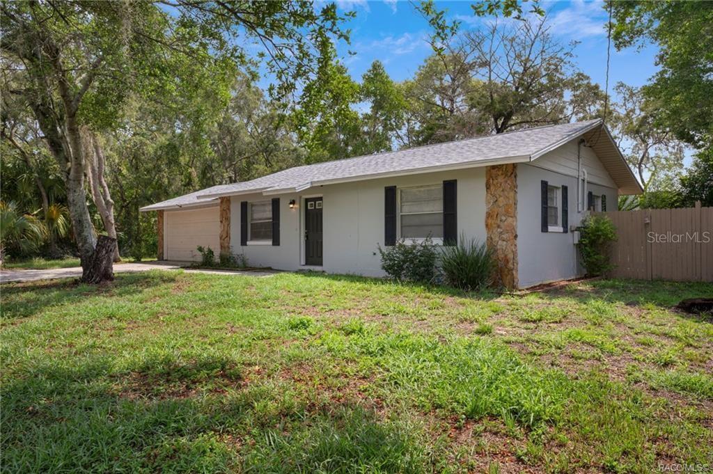 A single-story house with a stone-accented facade, a garage, and a large grassy yard — 63 N CROFT AVENUE, INVERNESS, FL