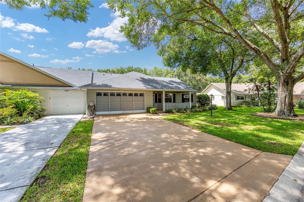 A single-story house with a two-car garage, a concrete driveway, and large shade trees — 8552 SW 92ND LANE UNIT D, OCALA, FL