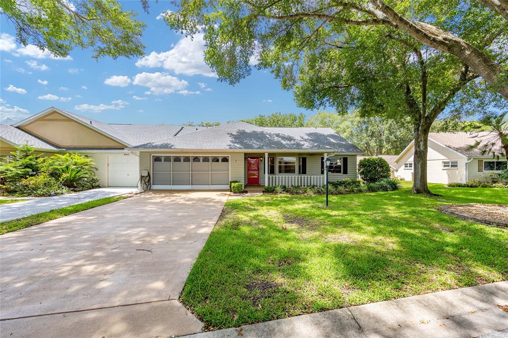 A single-story house with a red front door, a two-car garage, and a large tree — 8552 SW 92ND LANE UNIT D, OCALA, FL