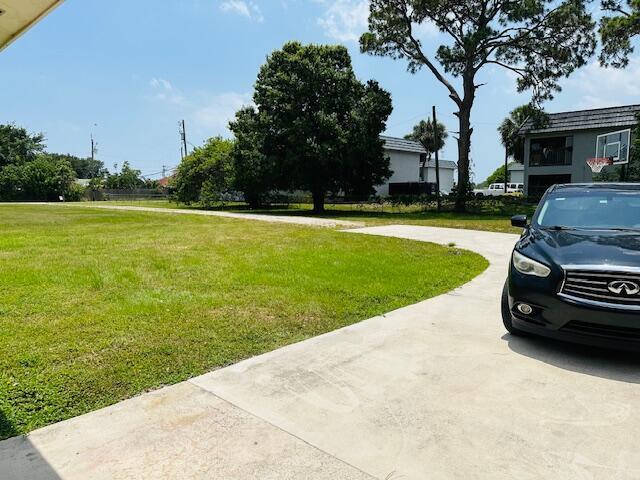 A black car is parked on a concrete driveway next to a large grassy lawn — 3421 Helena Drive, Lake Worth FL 33461, LAKE WORTH, FL