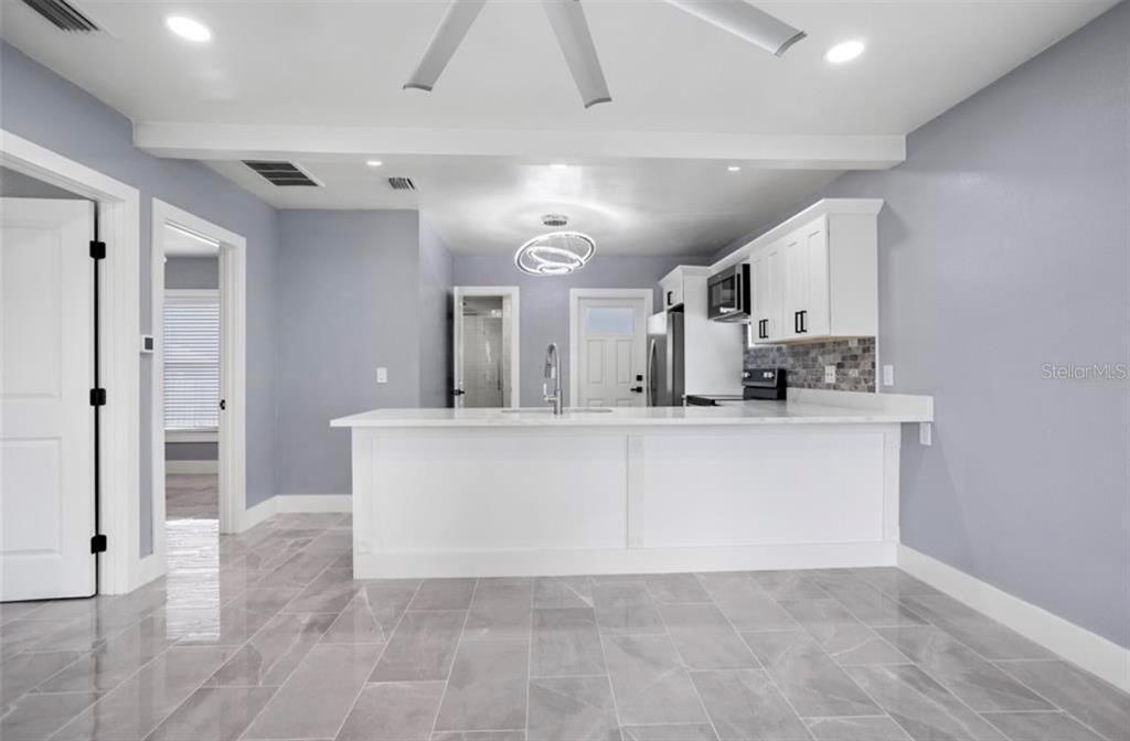 A kitchen features a white island, light gray walls, and gray tile flooring — 8907 N BOULEVARD, TAMPA, FL
