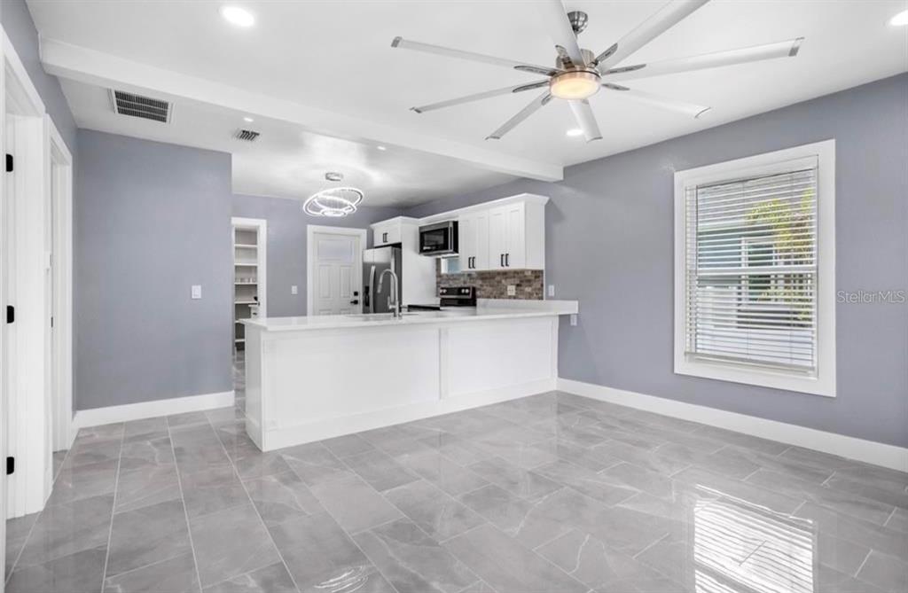 A kitchen with white cabinets, a breakfast bar, and gray tile flooring — 8907 N BOULEVARD, TAMPA, FL