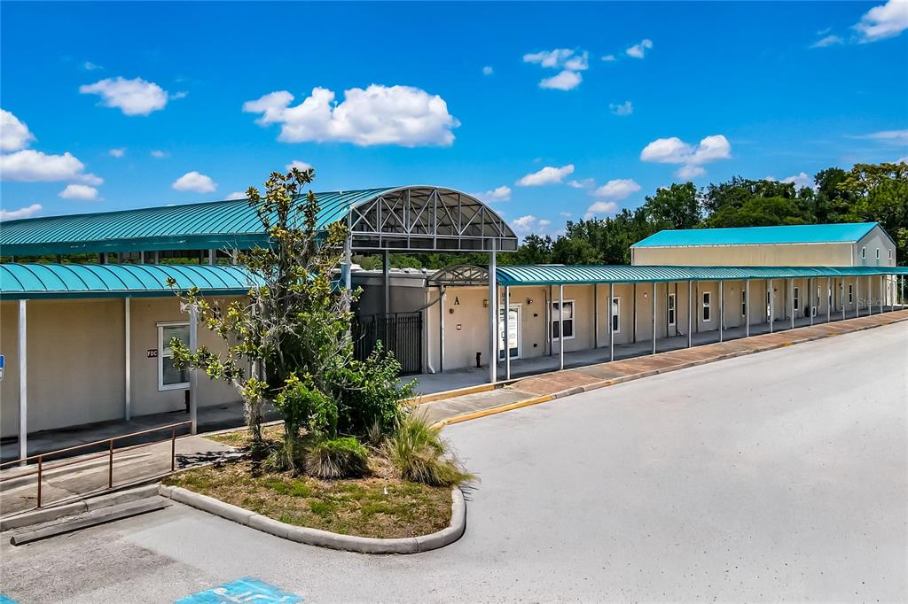 An aerial view shows a long, single-story commercial building with a teal roof and parking — 11734 JEFFERSON ROAD, THONOTOSASSA, FL