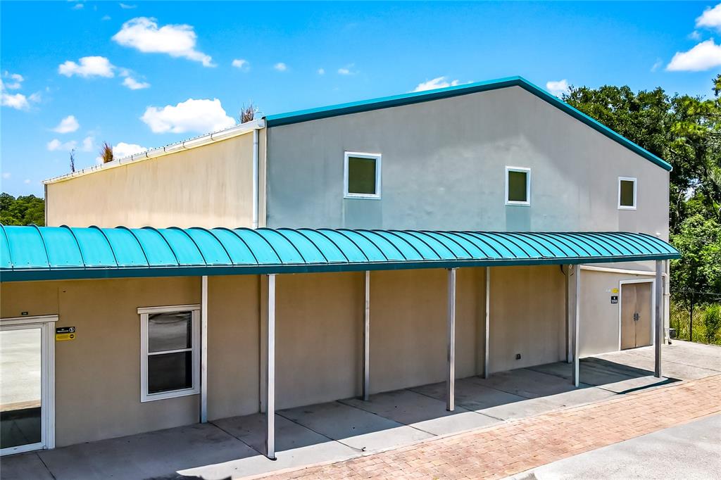 A single-story commercial building with a metal canopy stands behind a yellow security gate — 11734 JEFFERSON ROAD, THONOTOSASSA, FL