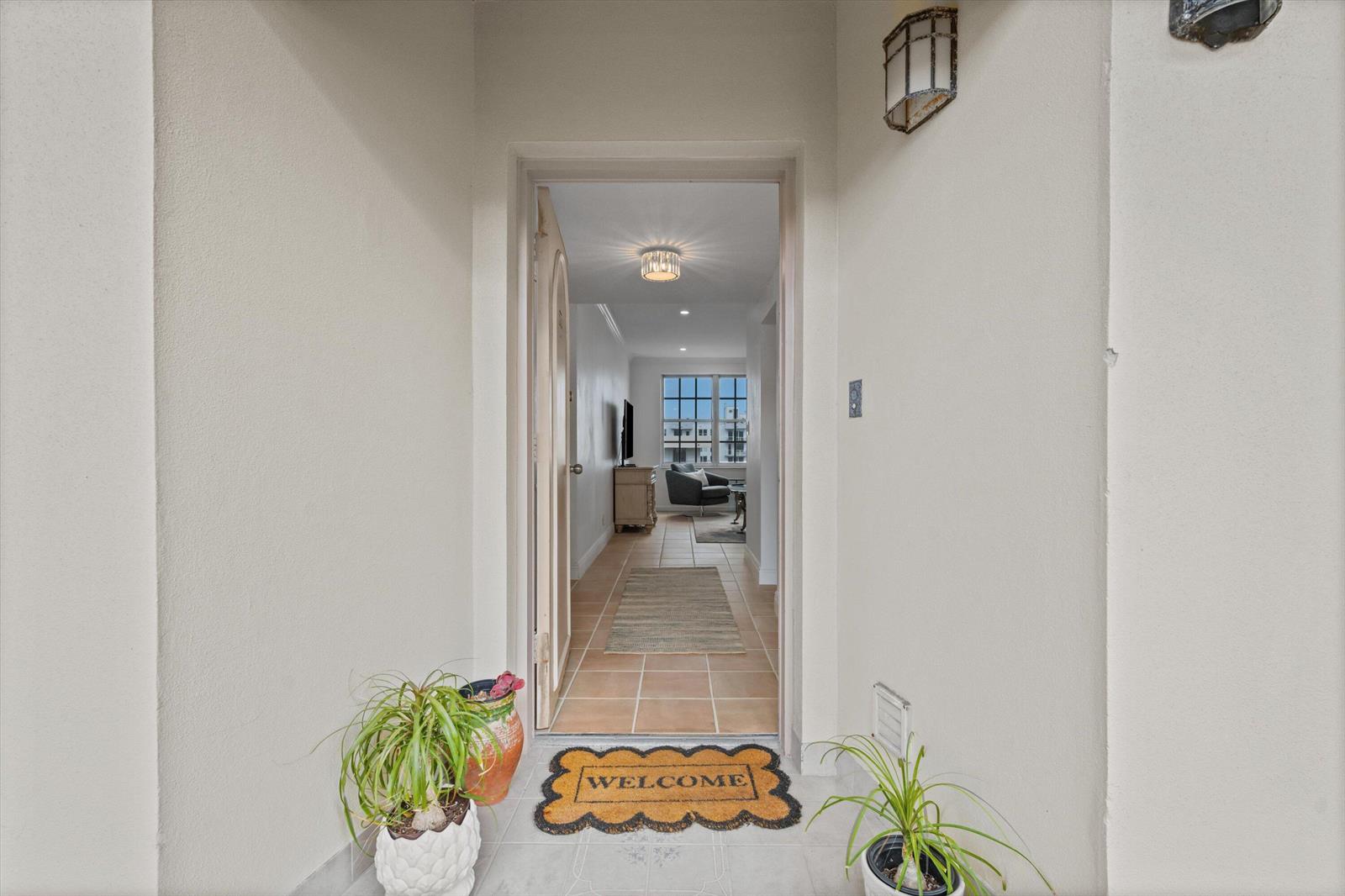 An entryway with a welcome mat leads into a tiled hallway of an apartment — 3475 S Ocean Boulevard # 715, Palm Beach FL 33480, PALM BEACH, FL
