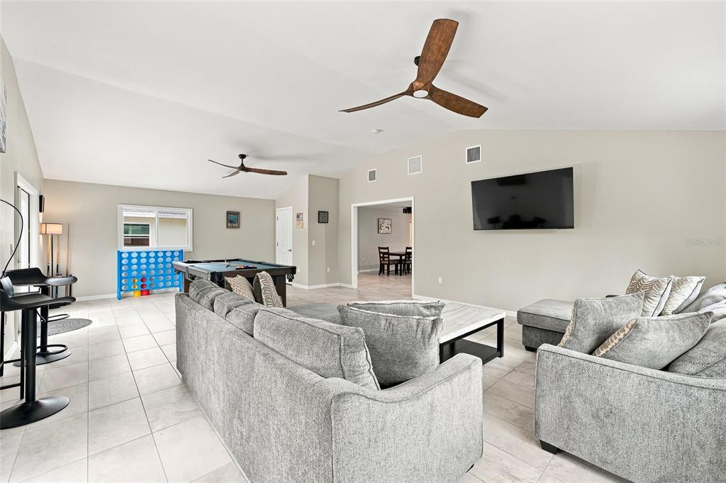 A spacious living room features gray sectional sofas, a pool table, and a ceiling fan — 608 SAINT JUDES DRIVE, LONGBOAT KEY, FL