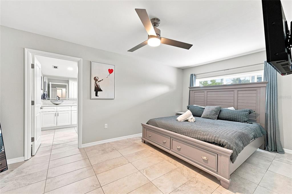 A bedroom features a gray bed with storage drawers, tile flooring, and an attached bathroom — 608 SAINT JUDES DRIVE, LONGBOAT KEY, FL