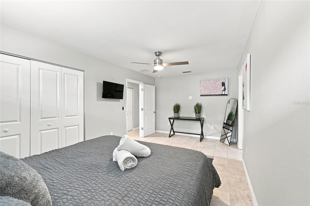 A bedroom features a gray bed, white closet doors, a ceiling fan, and a console table — 608 SAINT JUDES DRIVE, LONGBOAT KEY, FL