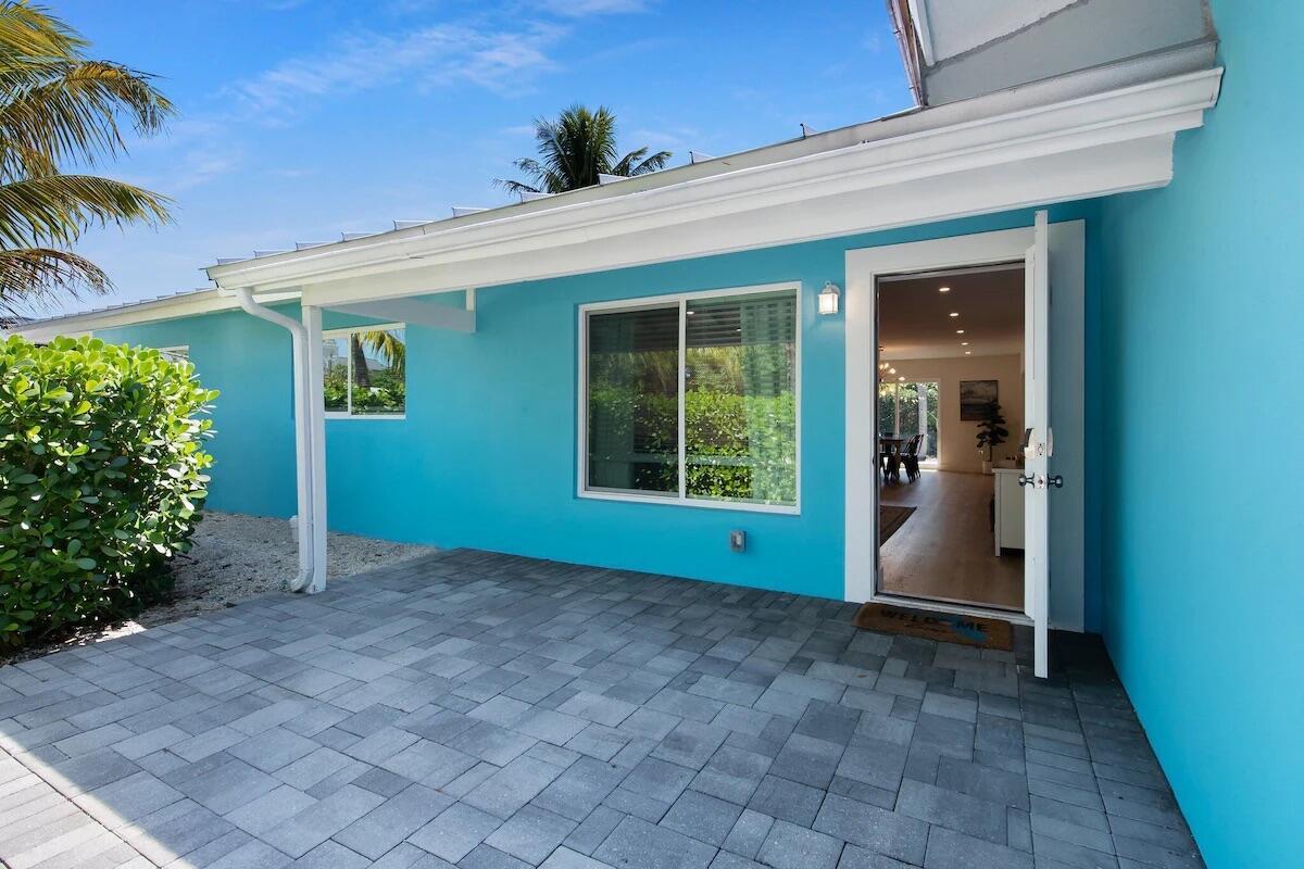 A bright blue exterior wall features a patio, a window, and an open doorway — 486 NE 29th Street, Boca Raton FL 33431, BOCA RATON, FL